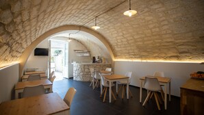 Un restaurante con techo de piedra abovedado, mesas y sillas de madera.
