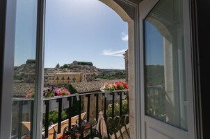 Uma varanda com vista para um edifício histórico e uma jardineira.