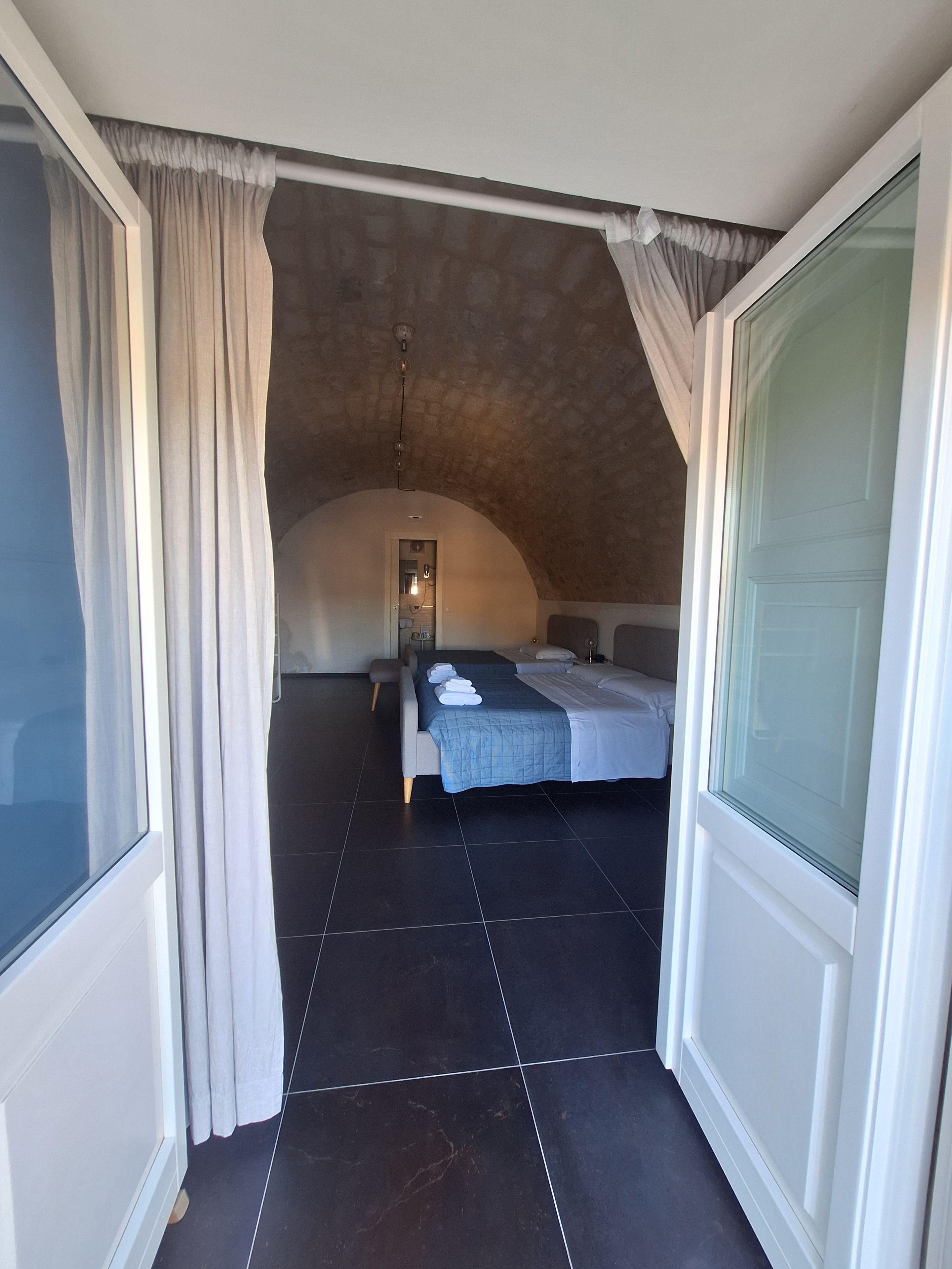 A bedroom with a large bed, a window, and a view of another room.