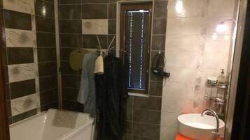 Un baño con bañera, lavamanos y ventana con persianas.
