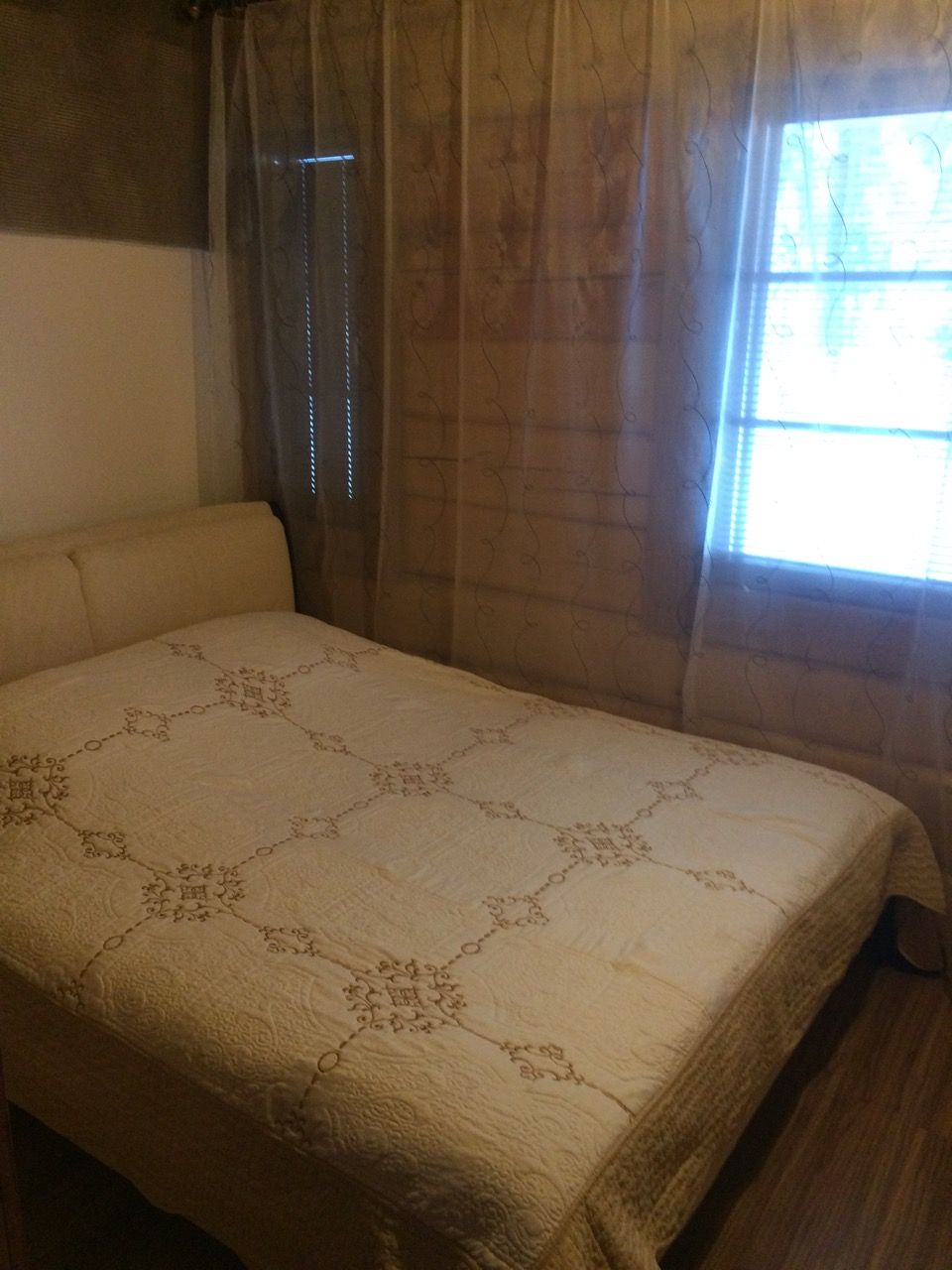 Een kamer met een bed, een raam met gordijnen en een muur.