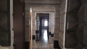 A corridor with stone walls and a wooden floor, leading to a door at the end. - Kalina Apartments (Savonlinna)