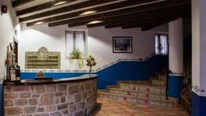 A hotel lobby with a stone reception desk, a staircase with patterned tiles, and a blue and white wall design. - Hotel Villa de Cabrales (Cabrales)