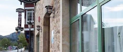 Kivinen rakennus, jonka edessä on kyltti, jossa lukee ”Hotel Villa de Cabrales”, ja sen edessä on ruukussa oleva kasvi.