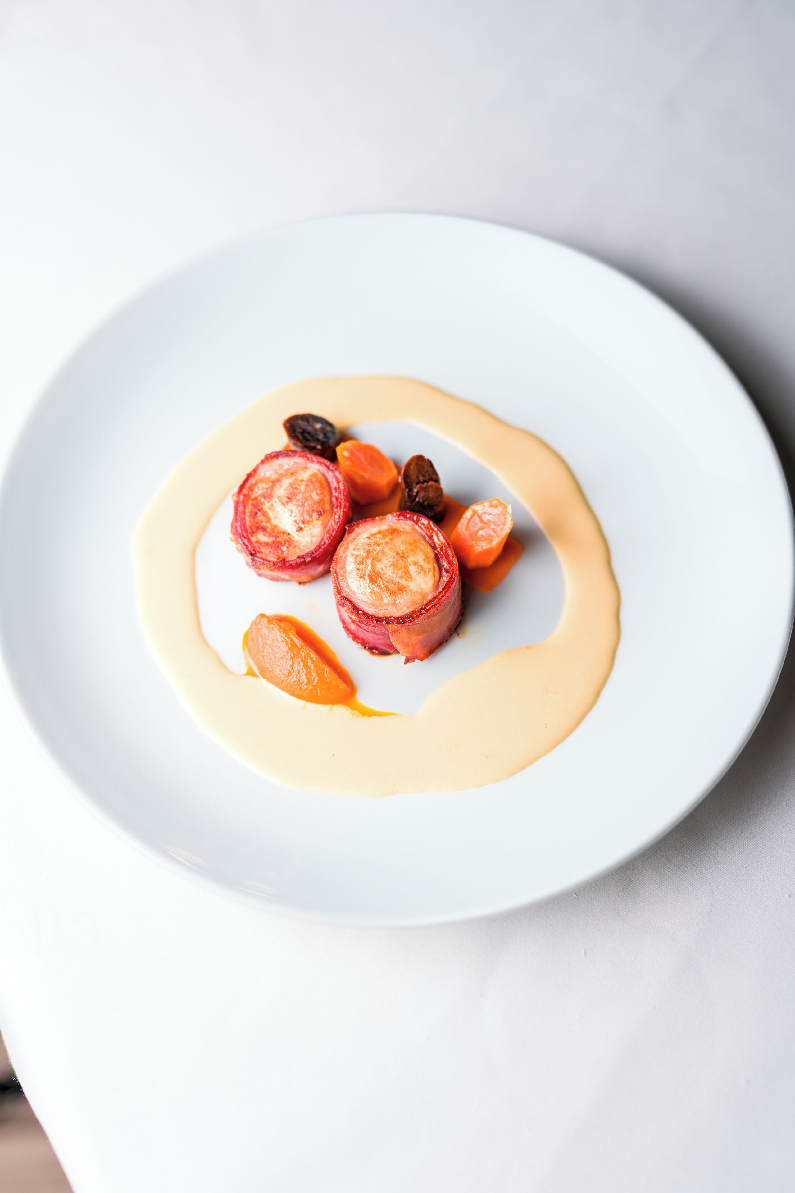 A white plate with a dessert consisting of sliced fruits and a dollop of cream.