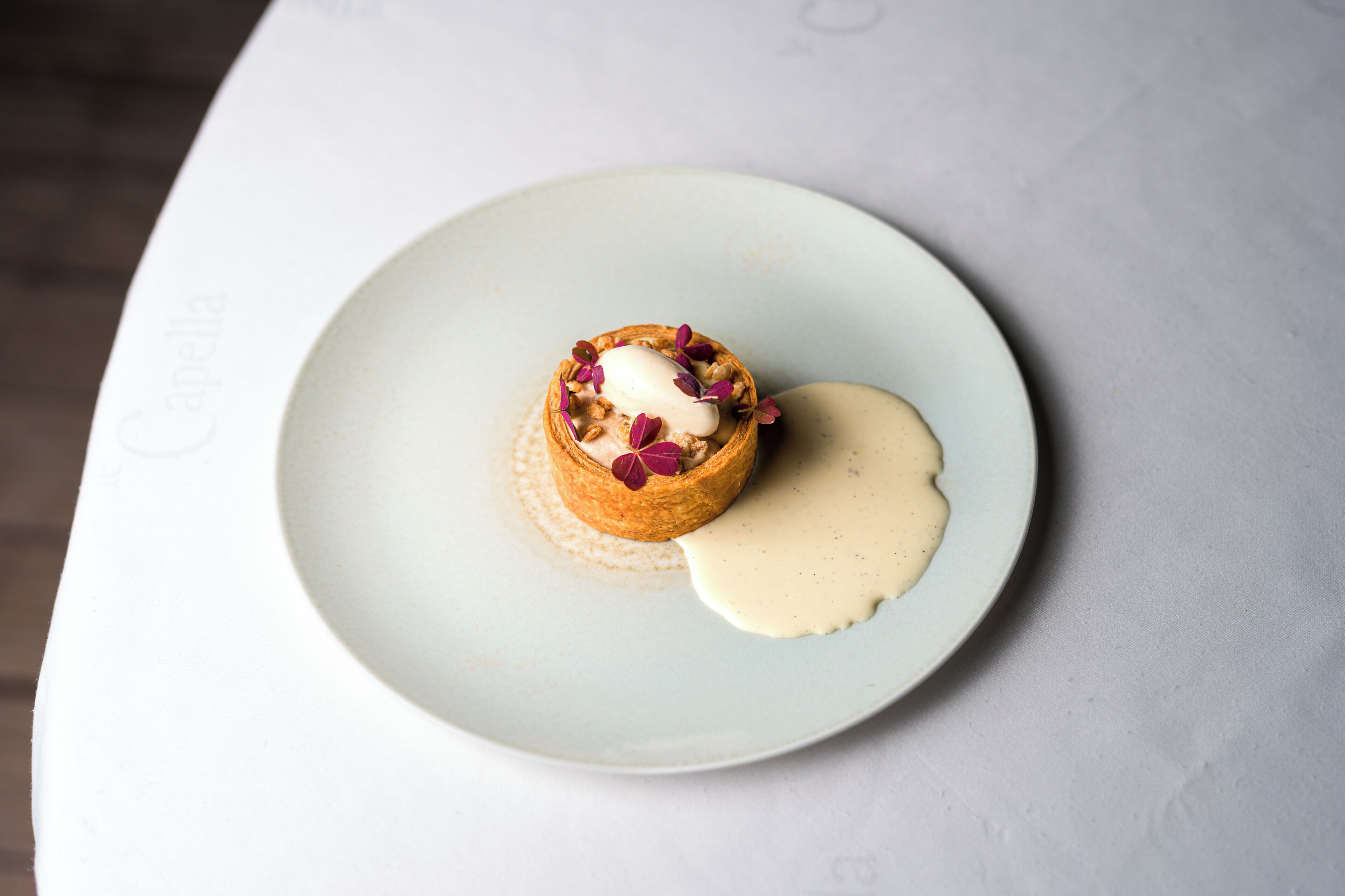 Un dessert servi dans une assiette, nappé d’une sauce crémeuse et agrémenté de noix.