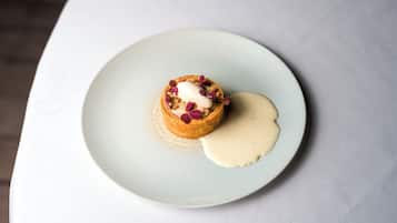 Un dessert servi dans une assiette, nappé d’une sauce crémeuse et agrémenté de noix.