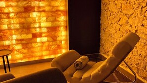 Un cuarto de spa con una silla de masaje, una mesita y una pared con textura.