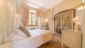 A bedroom with a four-poster bed, a vanity with a mirror, and a bust sculpture on the dresser. - Château Chapeau Cornu (Vignieu)