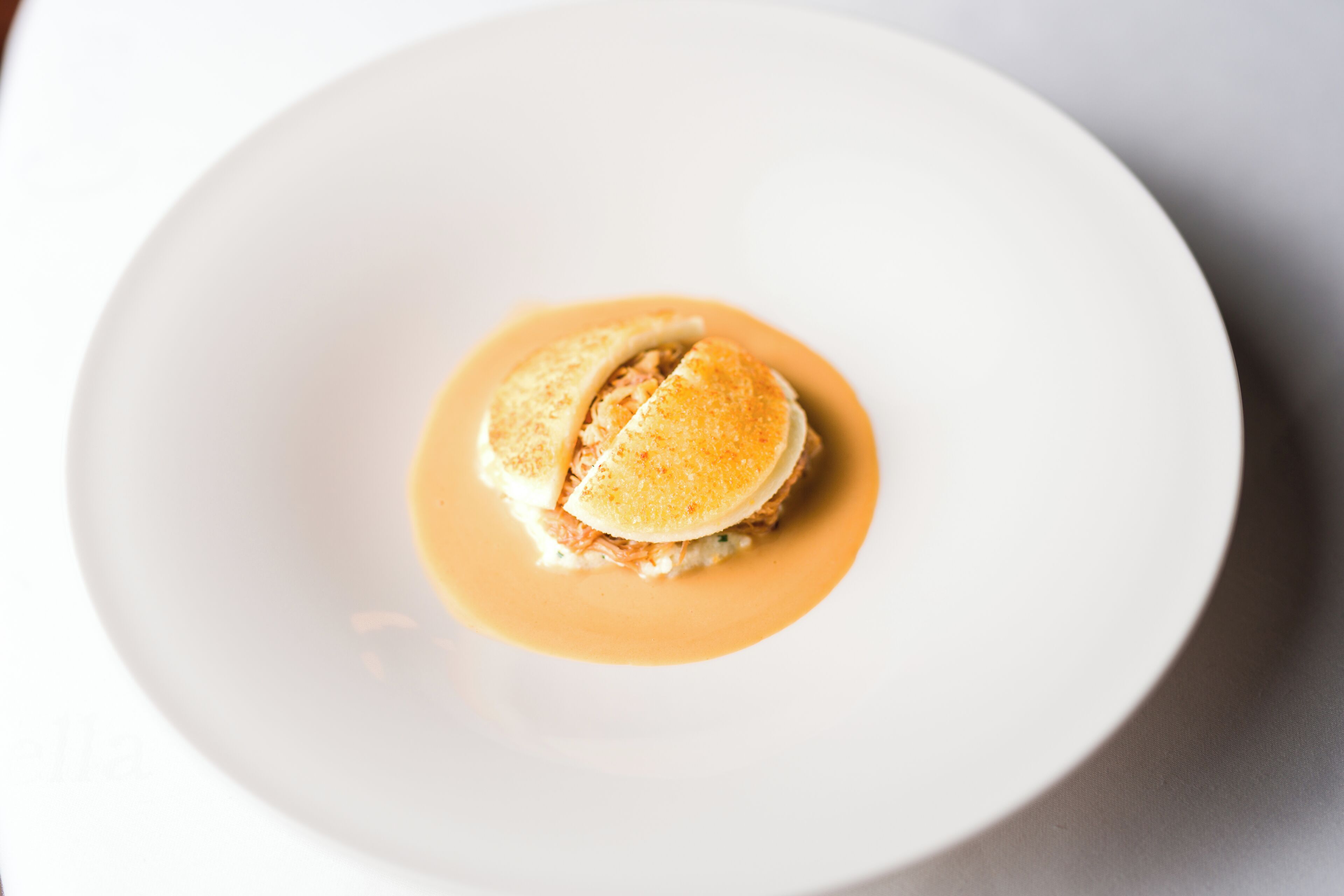 Un plato blanco con un postre que incluye un pastel y salsa.