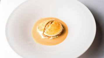 Un plato blanco con un postre que incluye un pastel y salsa.