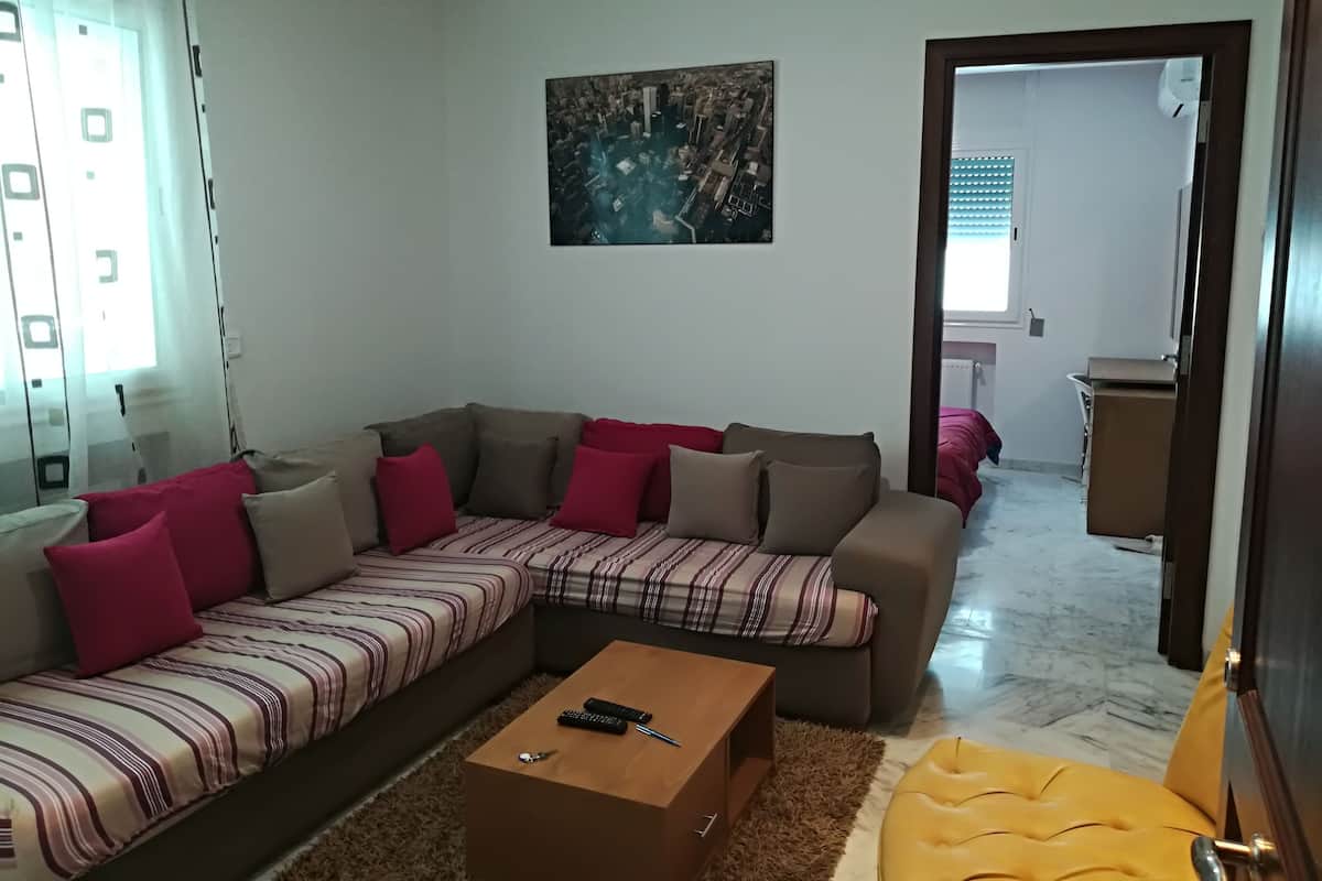 A living room with a sectional sofa, a coffee table, and a painting on the wall.