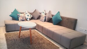 Ein modernes Wohnzimmer mit einem Ecksofa, einem runden Couchtisch und einem flauschigen Teppich.