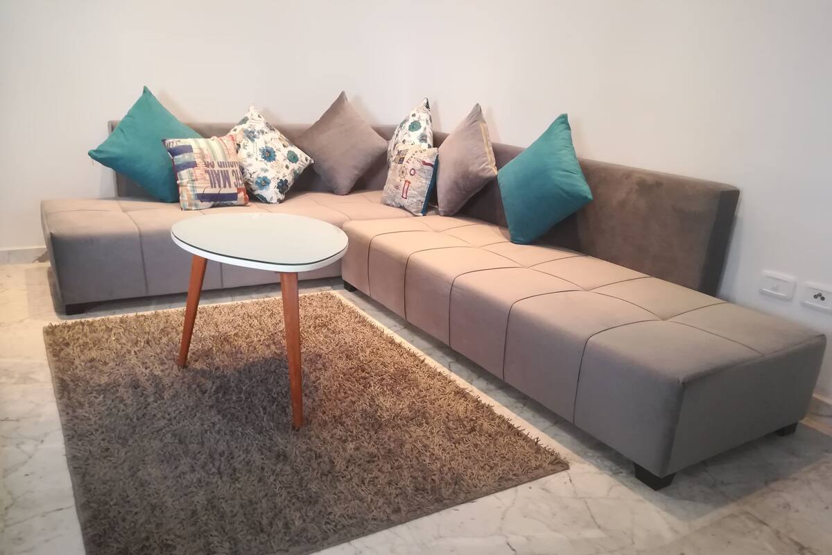 A modern living room with a sectional sofa, a round coffee table, and a shaggy rug.