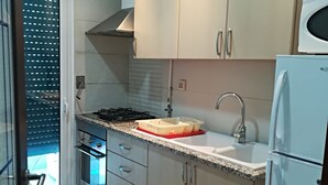Eine moderne Küche mit hellen Schränken, einer Edelstahl-Spüle und einer eingebauten Mikrowelle.