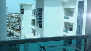 Ein modernes Gebäude mit mehreren Etagen und Balkonen, aufgenommen durch ein Fenster mit Metallgeländer.