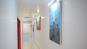 Un couloir aux murs blancs, aux portes rouges et orné d’œuvres d’art.