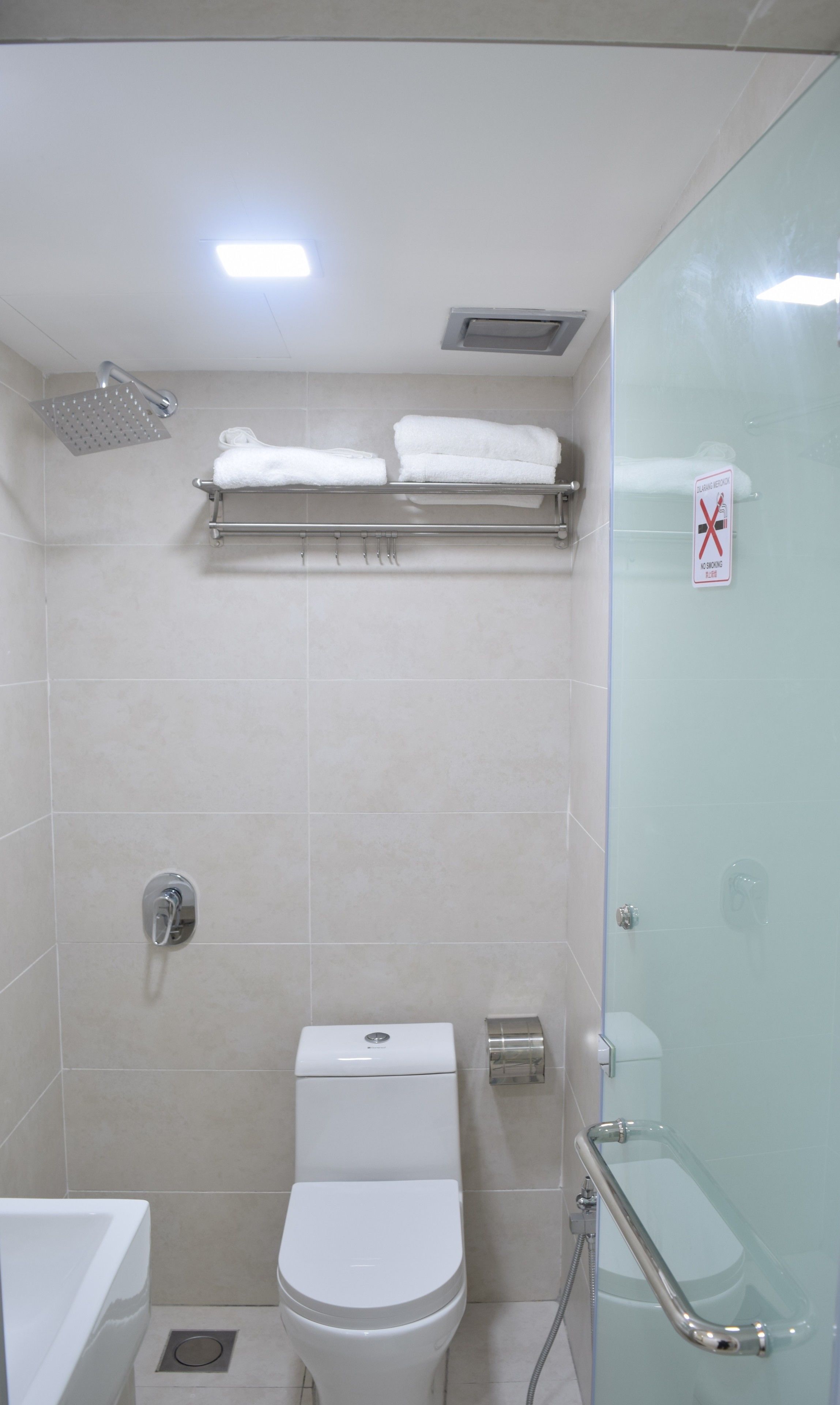 A modern bathroom with a toilet, shower, and glass-enclosed toilet stall.