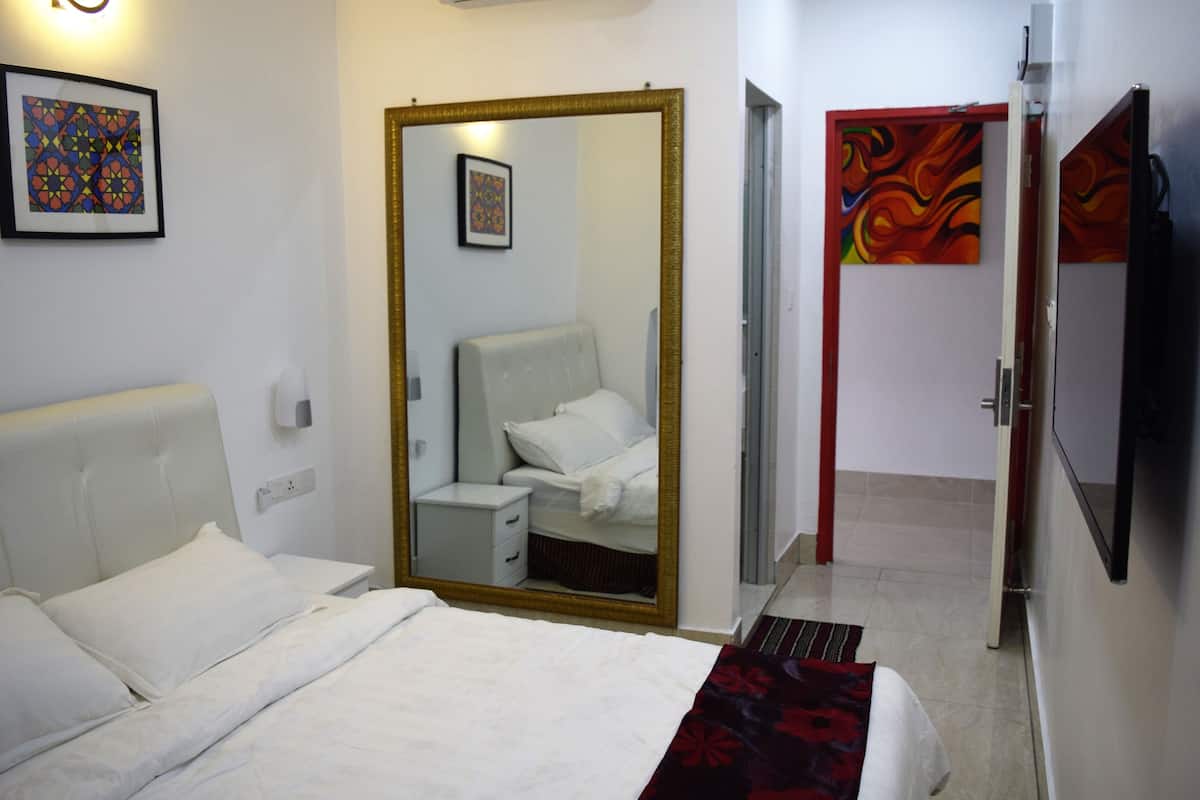 A hotel room with a bed, a bedside table, a mirror, a wardrobe, and a TV.