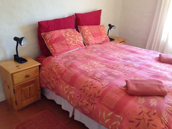 Une chambre à coucher avec un lit, deux tables de chevet, une lampe et un tapis rouge.