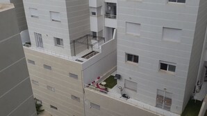 Ein mehrstöckiges Wohnhaus mit Balkonen, Klimaanlagen und einer kleinen Rasenfläche.