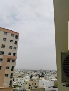 A residential area with multiple buildings, including a multi-story apartment building with a beige facade and a large window on the right side.