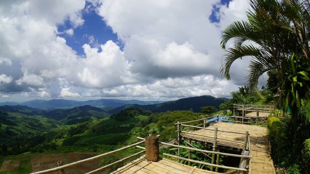 A bamboo staircase leading to a platform with a view of green hills and a cloudy sky. - Phusawantawansuay Resort (Thoeng)