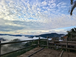 Guarda de bambu com vista para uma paisagem montanhosa e nevoenta, sob um céu claro.