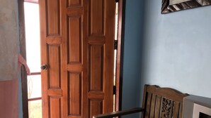 A wooden door with a handle, a wooden chair with a metal armrest, and a television set. - Phusawantawansuay Resort (Thoeng)