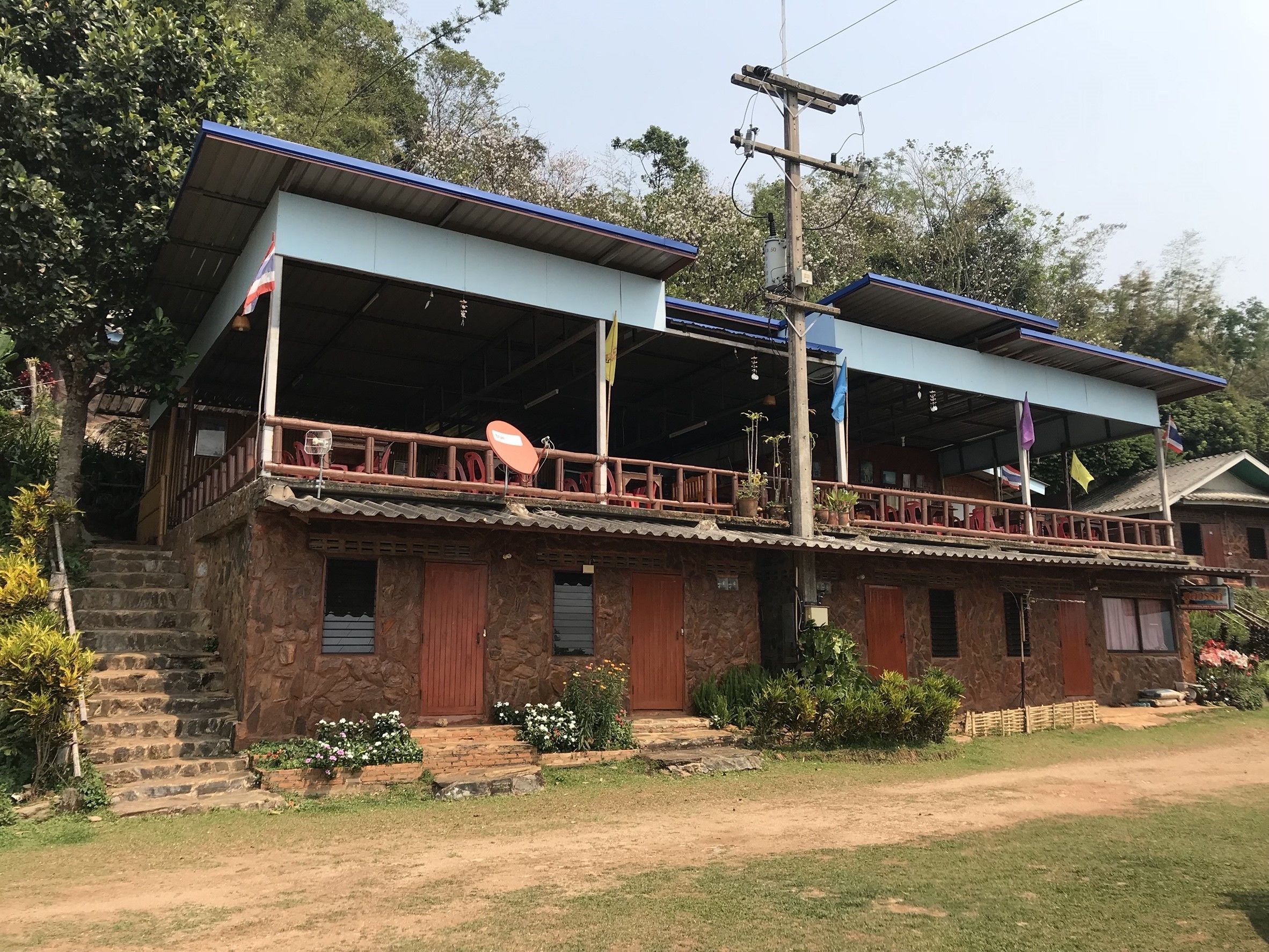 A two-story building with a balcony, stone walls, and a flag.