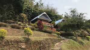 A hillside property with a stone staircase leading up to a house with a blue roof. - Phusawantawansuay Resort (Thoeng)