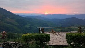 A sunset view from a wooden deck overlooking a valley with a dog sitting on it. - Phusawantawansuay Resort (Thoeng)