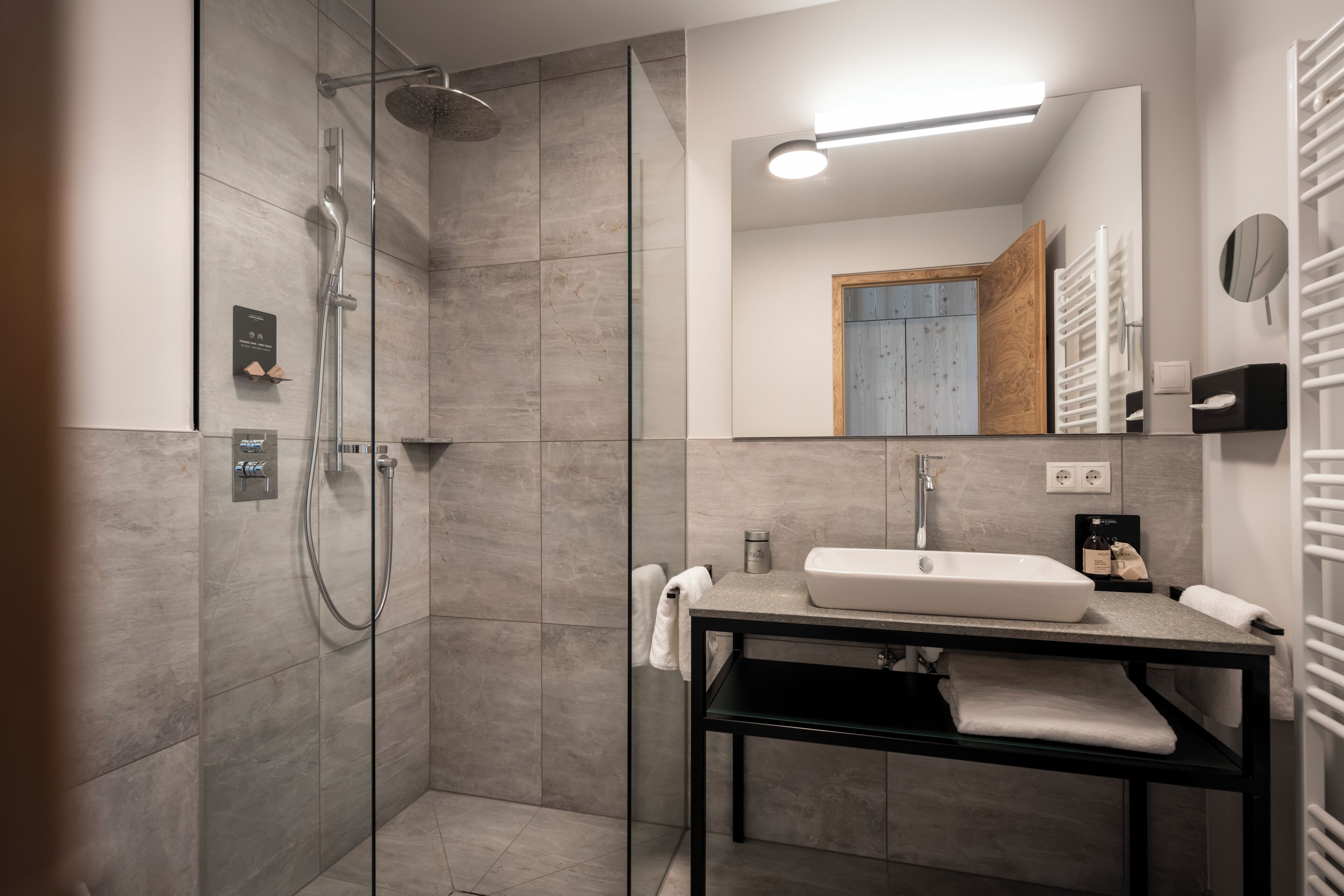 A modern bathroom with a glass-enclosed shower, a black vanity with a sink, and a mirror.