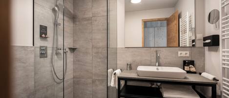 A modern bathroom with a glass-enclosed shower, a black vanity with a sink, and a mirror.