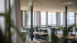 A restaurant with multiple tables and chairs, large windows, and a view of the outdoors. - Das Mühlwald Quality Time Family Resort (Naz Sciaves)