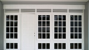 A set of white double doors with multiple glass panels, set in a building with a tiled floor. - MK House Tendean (Jakarta)