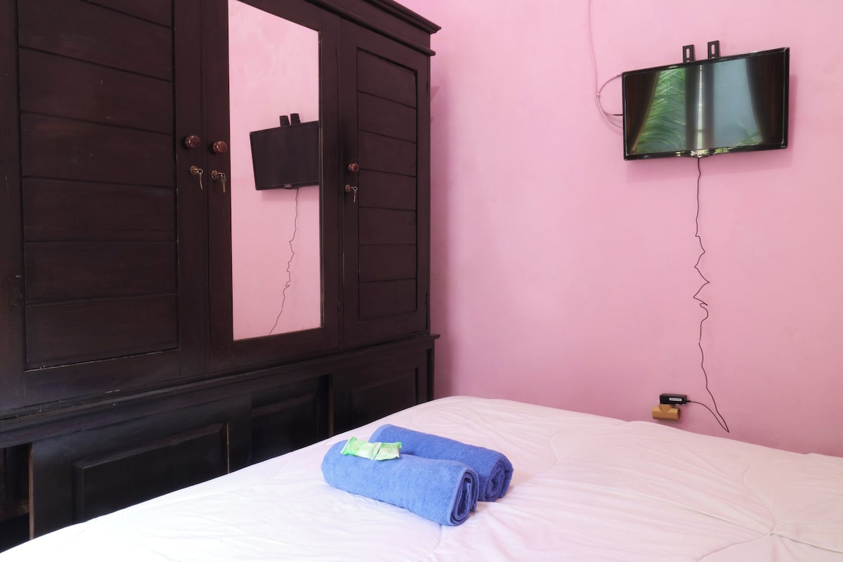 A bedroom with a bed, a wardrobe, and a TV mounted on the wall.
