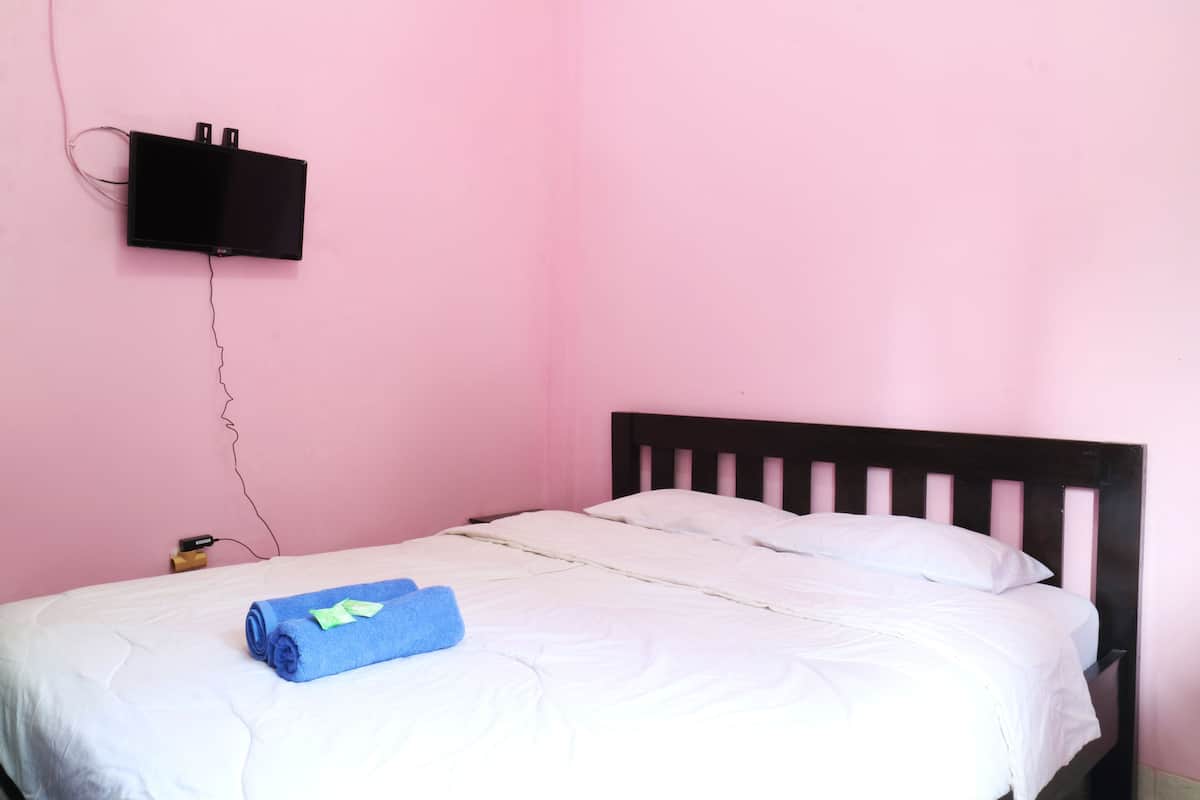 A single bed with white bedding, a black headboard, and a blue towel on the bed.