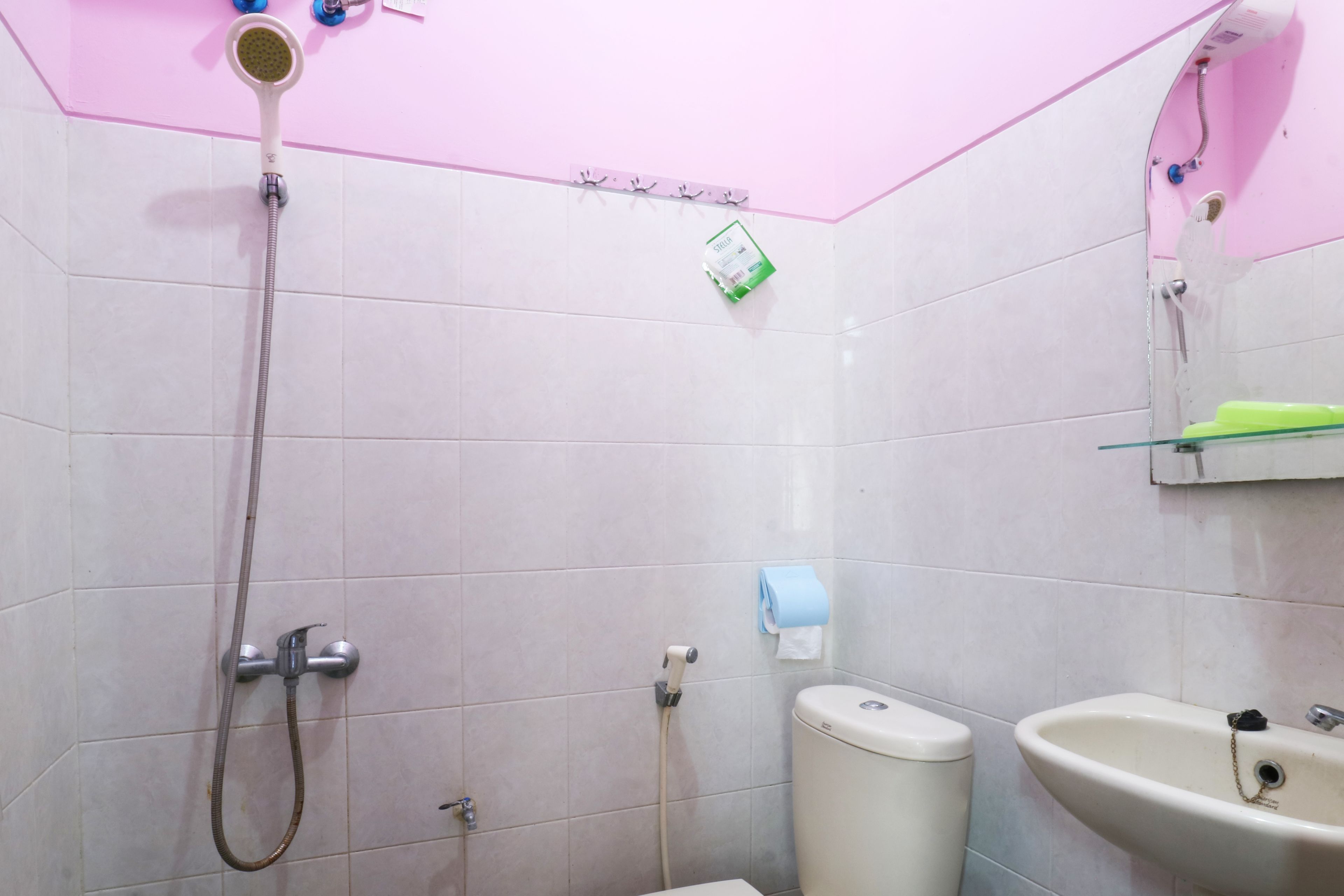 Un baño con azulejos blancos, ducha, inodoro y lavabo.