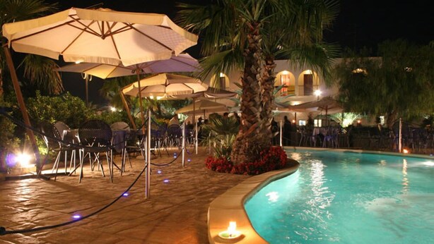 An outdoor pool area with umbrellas, chairs, and a palm tree. - Casale dei Fornici (Polignano a Mare)