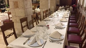 A long dining table set with white tablecloths, plates, glasses, and cutlery, surrounded by wooden chairs. - Casale dei Fornici (Polignano a Mare)