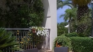 An outdoor patio with two dark-colored chairs and a table, surrounded by potted plants and a decorative railing. - Casale dei Fornici (Polignano a Mare)
