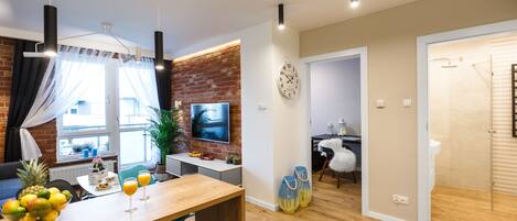 A modern living room with a dining area, a TV, and a brick wall.