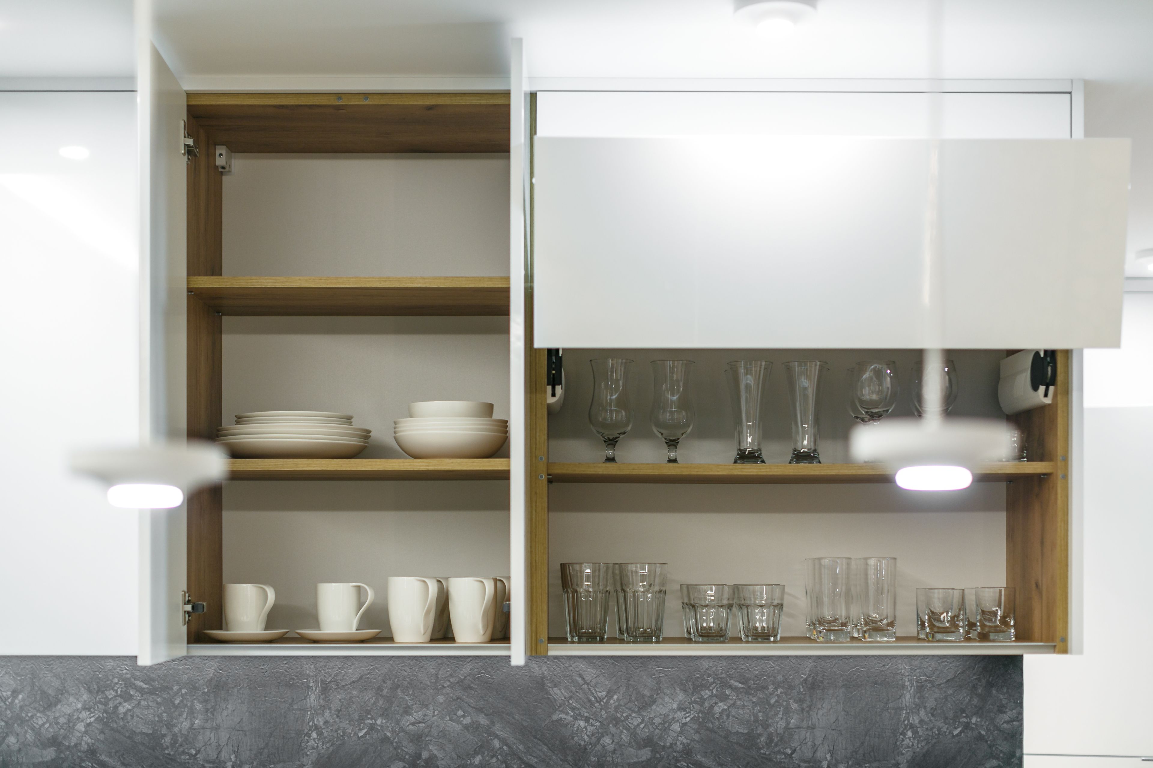 A kitchen with open cabinets displaying bowls, cups, and glassware.