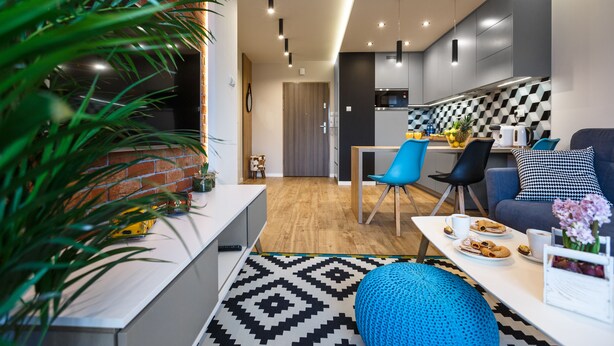 Ein modernes Wohnzimmer mit Essbereich, Küche und einer sichtbaren Tür zu einem weiteren Raum.