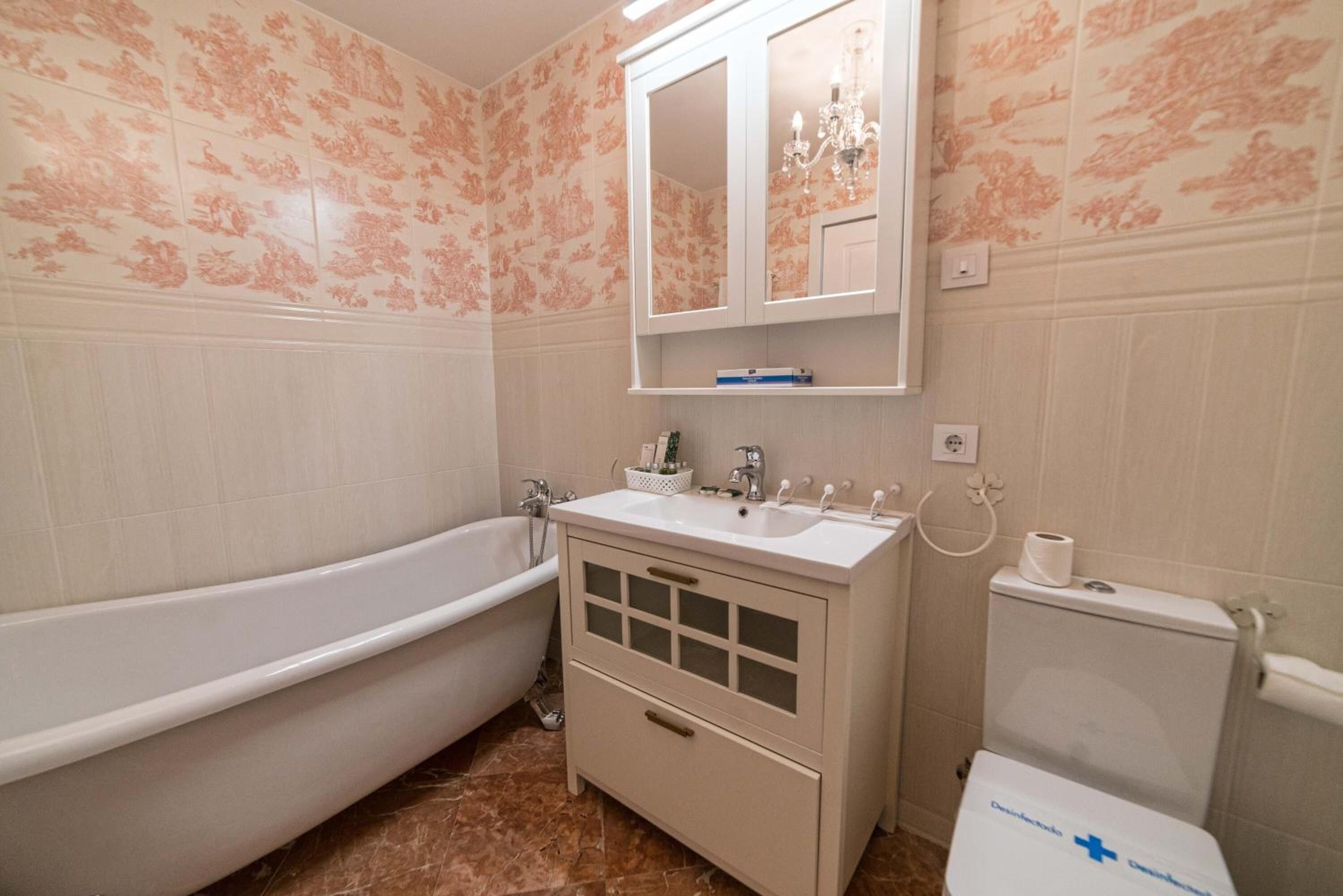 A bathroom with a freestanding bathtub, a vanity with a mirror, and a toilet.