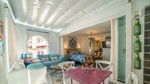 A cozy living area with a blue sofa, white armchairs, and a small table with a vase of flowers. - Rey Don Pedro Luxury Home (Seville)