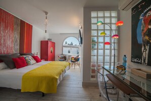 Una habitación de hotel moderna con una cama grande, un escritorio, una silla y una ventana con lámparas de colores.