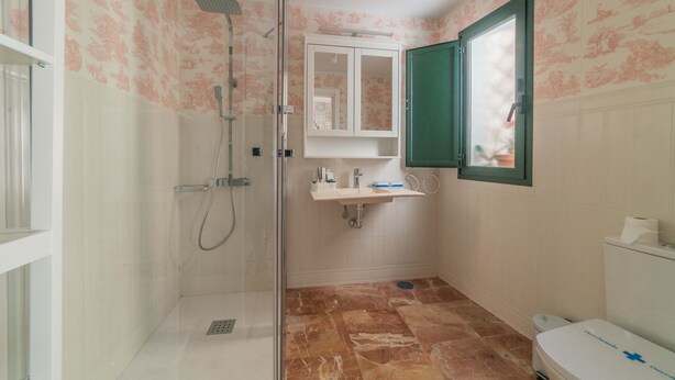 A bathroom with a shower, sink, toilet, and a mirror. - Rey Don Pedro Luxury Home (Seville)