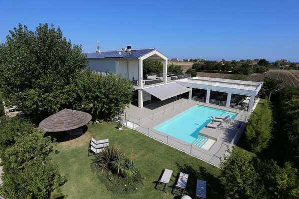 A modern house with a swimming pool, a covered patio, and a garden.